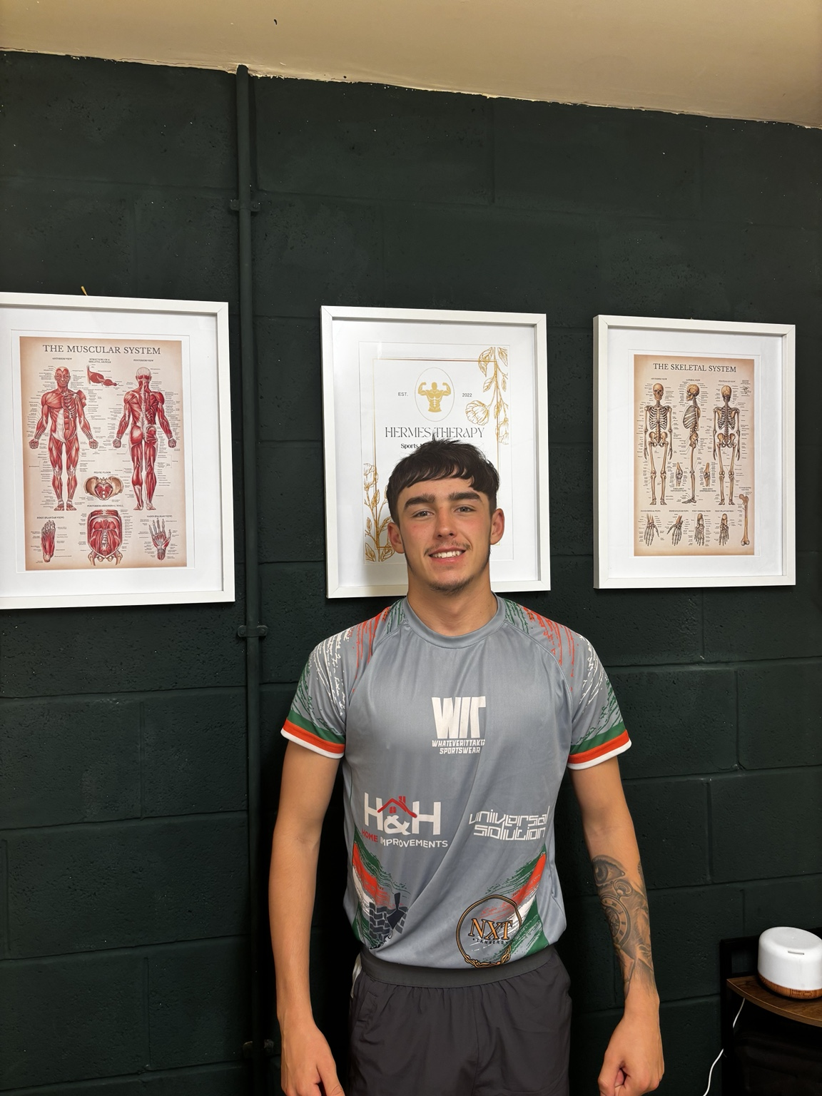Hermes Therapy client standing in front of the clinic anatomy displays